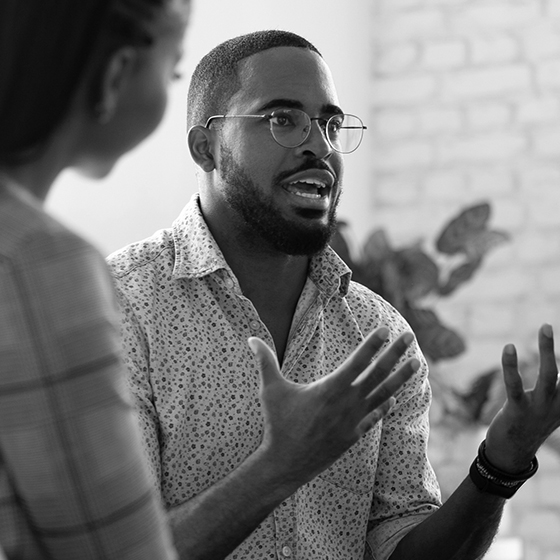 man speaking with his hands with others listening